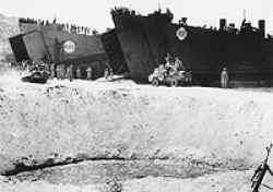 HM LST-62 (on the right) and HM LST-405 beached, 3 September 1943 (Invasion Day) at Reggio Italy, while unloading vehicles.Notice the bomb crater in the front of the picture.