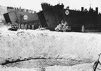 HM LST-62 (on the right) and HM LST-405 beached, 3 September 1943 (Invasion Day) at Reggio Italy, while unloading vehicles.Notice the bomb crater in the front of the picture.