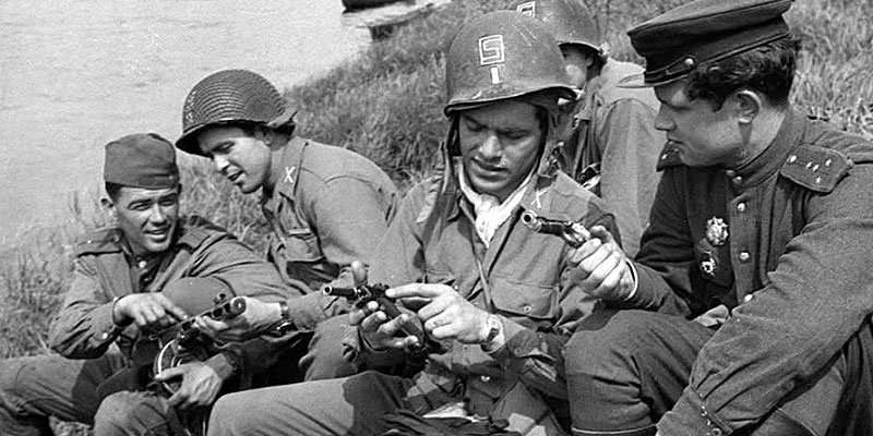 Examining and comparing each other's service pistols and sidearms in a moment of relaxed curiosity.