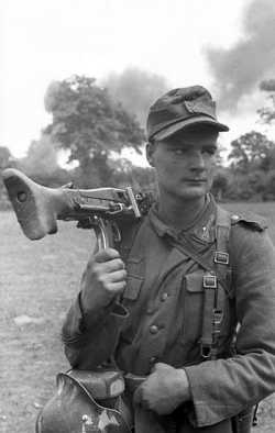 A felllow soldier of the 275th Infantry Division in Normandy carrying an MG42 over his shoulder