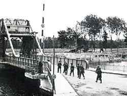 Another picture of the Pegasus Bridge if you take a closer look you will see the same Horsa gliders in the background as in the picture above this one. Transport moving across the Caen Canal Bridge at Benouville. The bridge was renamed Pegasus Bridge, after the mythical winged horse on the formation sign of British airborne forces.