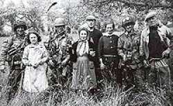E Company blending in with the local population, Normandy, France. Forrest is standing on the far left.