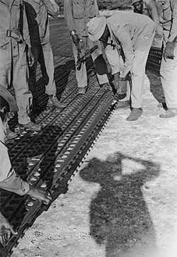 American soldiers in the 870th Aviation Engineering Battalion putting down Marston Mat/pierced steel planking [PSP] to create a runway. Hollandia Airfield, Hollandia, New Guinea, Dutch East Indies [modern-day Jayapura, Papua, Indonesia]. 1944