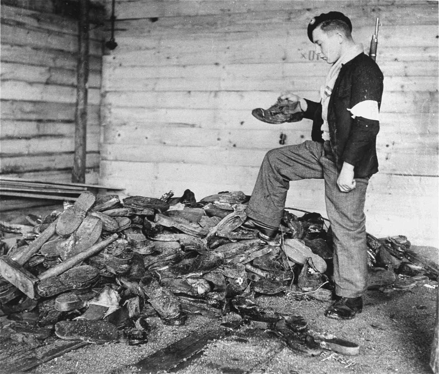 French resistance examines boots, shoes and wooden clogs piled near a furnace in the crematorium
